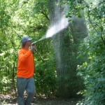 Skeeter Beater technician applying mosquito and tick barrier treatment in a Crystal Lake yard